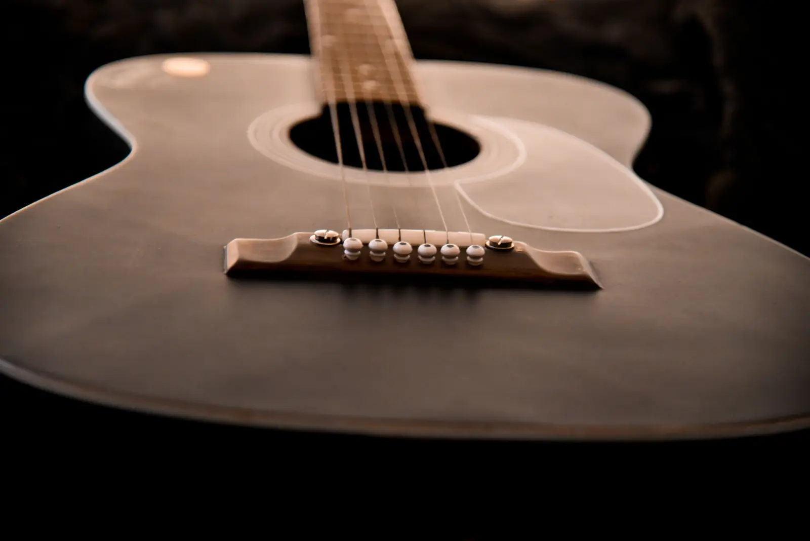 The bridge and soundhole of an acoustic guitar, photographed close